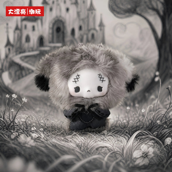 A fluffy grey-toned doll pendant with black accents resting on grass.