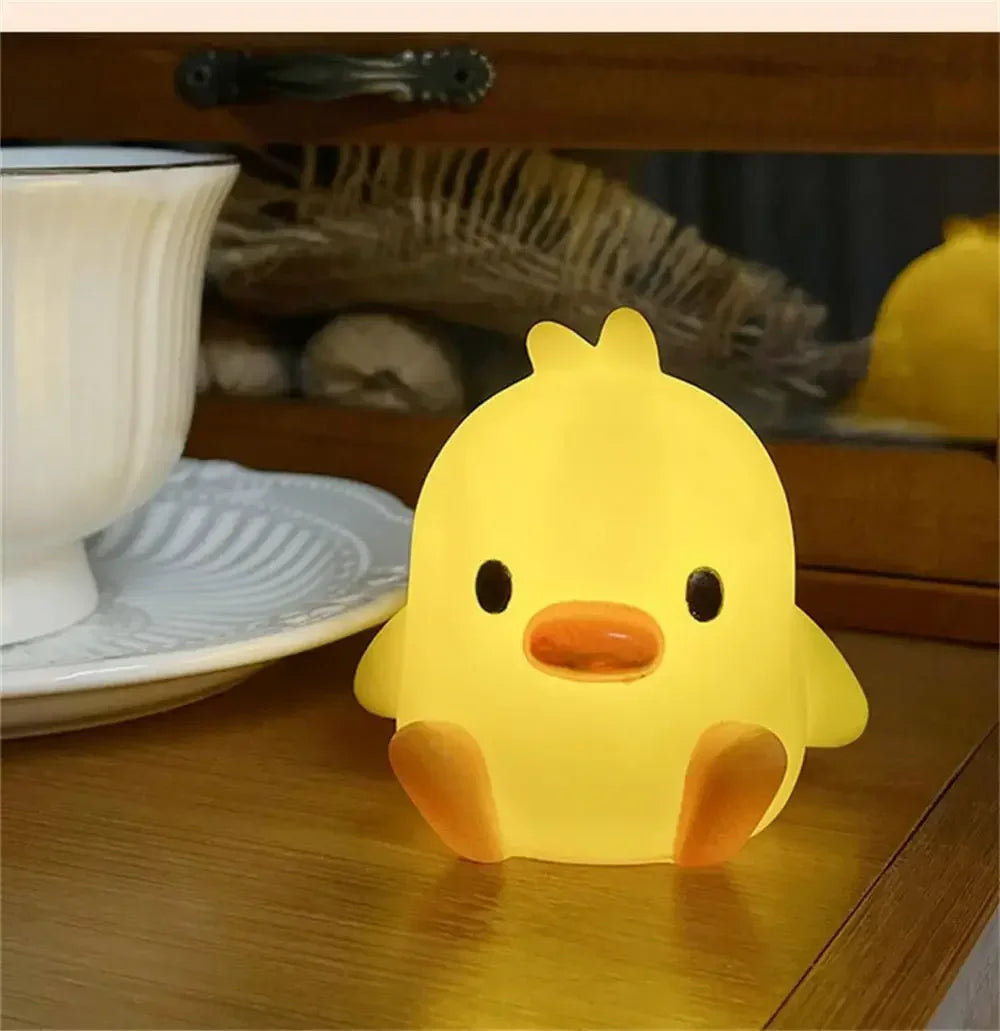A glowing yellow cartoon duck night light sitting on a wooden surface next to a white bowl.