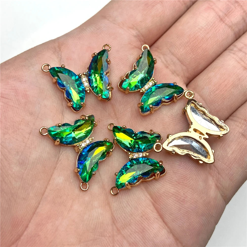 Gold-toned crystal butterfly charm beads for jewelry making displayed on a hand.