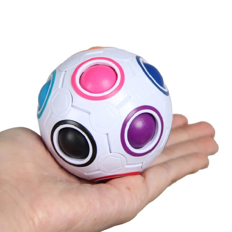 A hand holds a colorful rainbow antistress cube fidget toy with multiple colored panels.