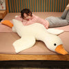 A person is relaxing on a pink surface with an extra-large white plush goose pillow.
