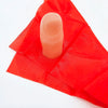 Un doigt rose de rechange est posé sur un tissu de soie rouge pour un tour de magie.