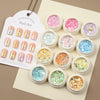 A set of iridescent opal and mermaid chrome nail glitter pigments displayed in small jars on a card.