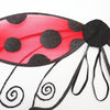 Costume d'une coccinelle rouge avec des ailes translucides rouges à pois noirs et des antennes noires.