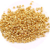 A pile of small, gold-colored metallic glass beads for jewelry making.