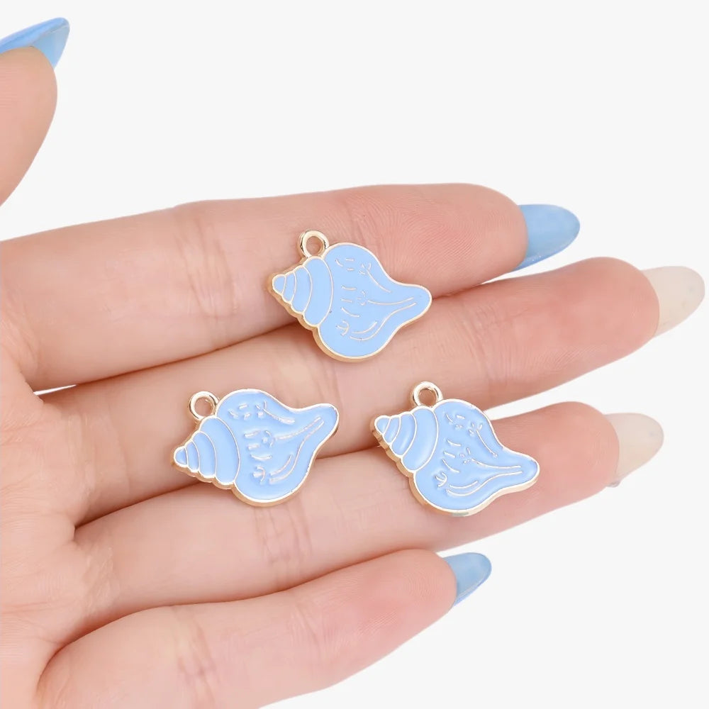 Two light blue enamel marine life charms resting on a person's hand.