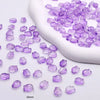 A collection of purple gradient glass beads is displayed next to a white tool, showing various sizes and shapes for jewelry m