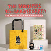A yellow tote bag featuring a black monster design is displayed next to a white box containing a packaged product for The Mon