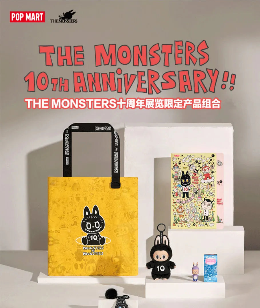 A yellow tote bag featuring a black monster design is displayed next to a white box containing a packaged product for The Mon