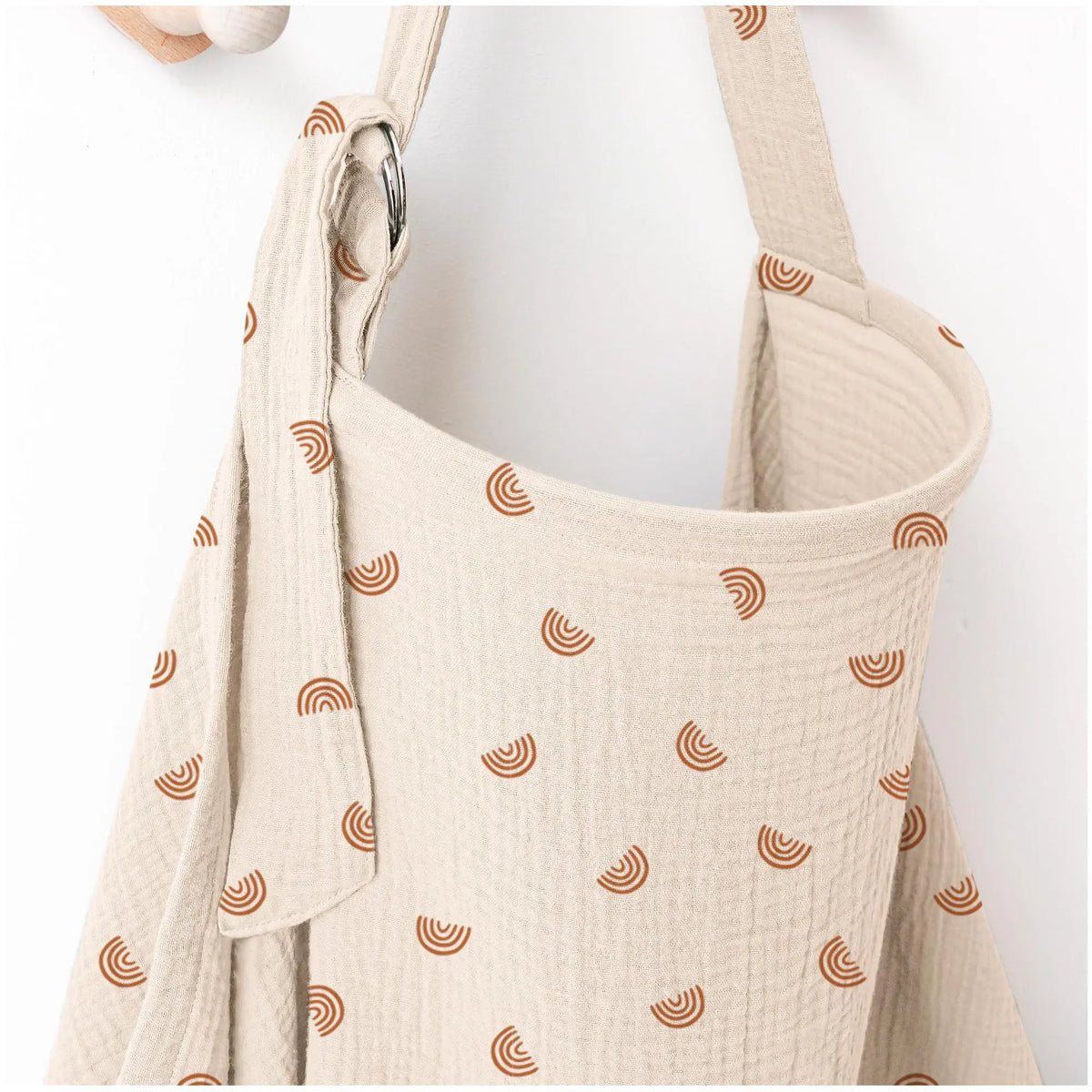 A beige breathable muslin nursing cover with a textured pattern and adjustable neckline.