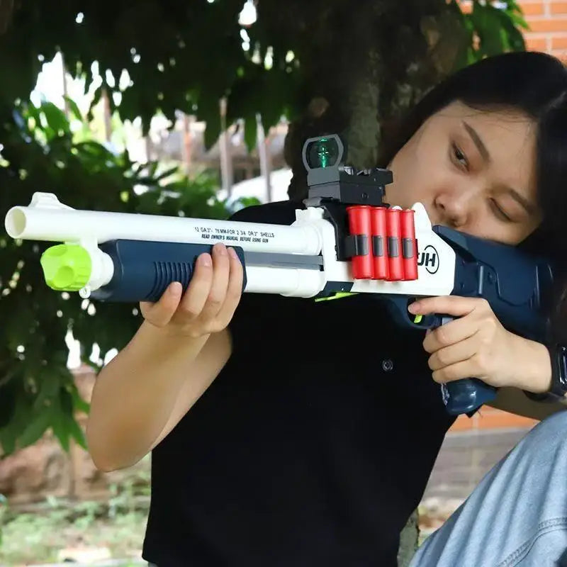 A young woman holds a white and black soft bullet shotgun toy with red shells, outdoors.