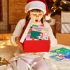 A young child wearing a Santa hat is looking at a red sticker book with animal scenes and learning activities.