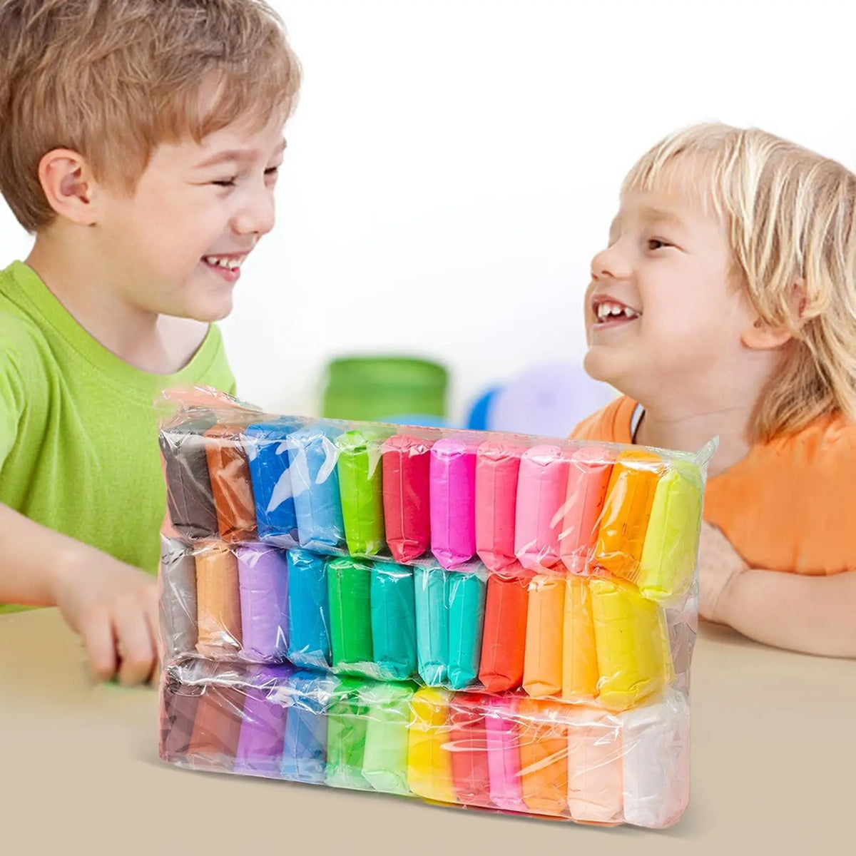 A colorful set of vibrant air dry modeling clay tubes in various colors is displayed on a table with two smiling children.