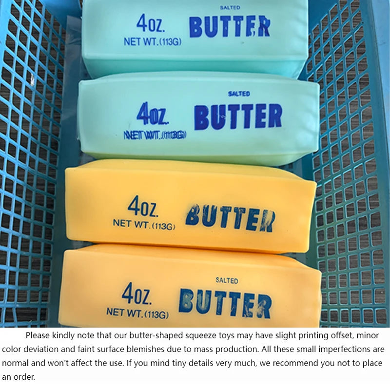 Four butter-shaped squishy toys in various colors are displayed in a blue mesh container.