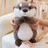 A soft, gray and white magnetic otter plush toy is being held by a person in a light-colored setting.