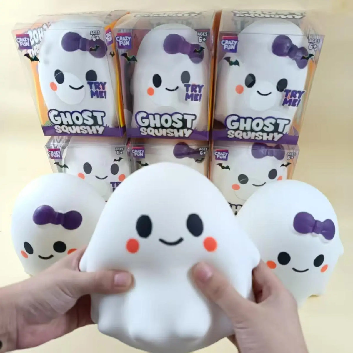 Hands hold a white ghost squishy stress relief toy next to packaged versions.