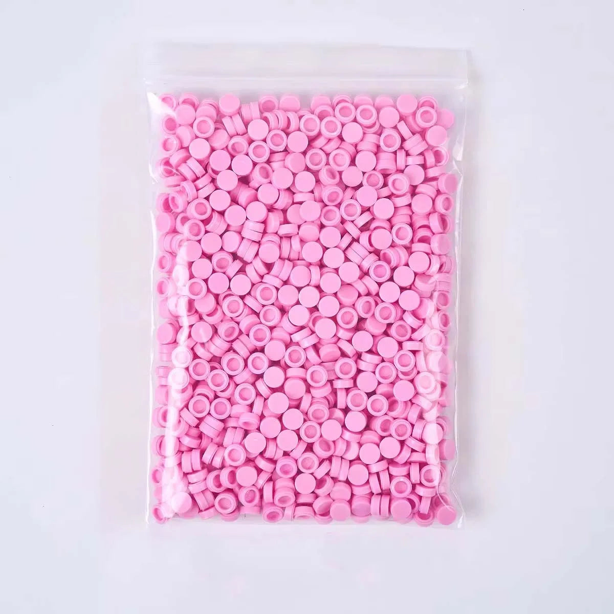 A clear plastic bag filled with numerous pink plastic beads or filler for crafting.