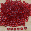 A pile of bright red glass beads shaped like tulip flowers on a beige surface.