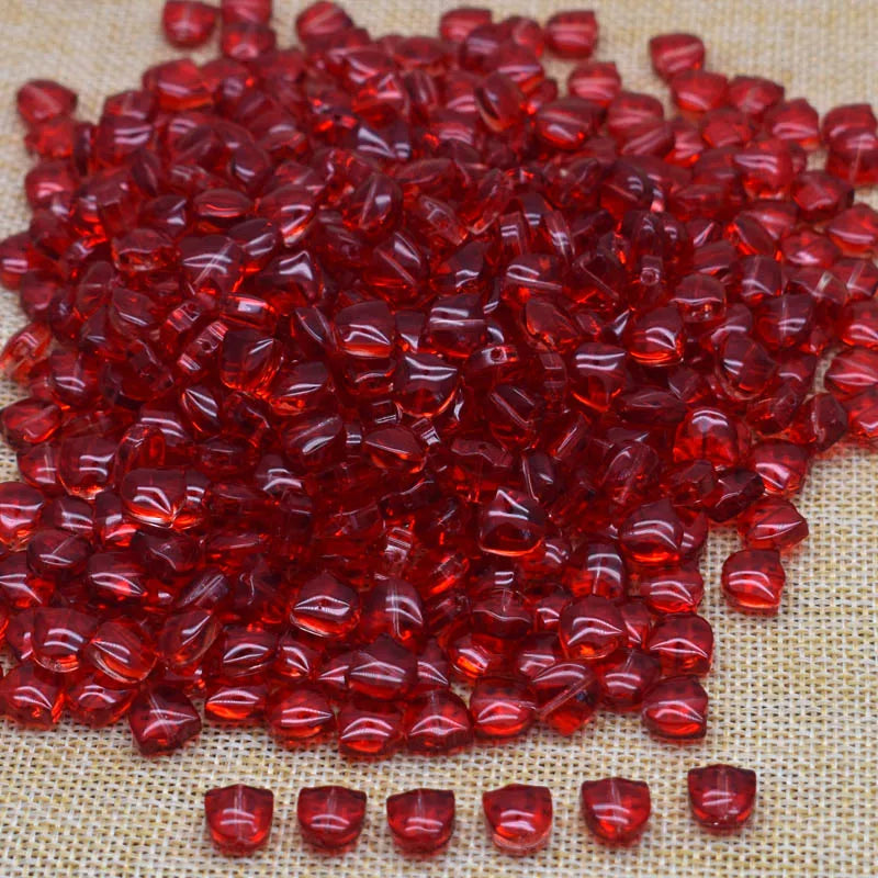 A pile of bright red glass beads shaped like tulip flowers on a beige surface.