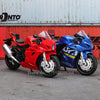 A red and blue 1:18 scale die-cast motorcycle model displayed in an outdoor setting.