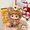 A fluffy brown animal plush doll with large eyes is displayed on a wooden surface.