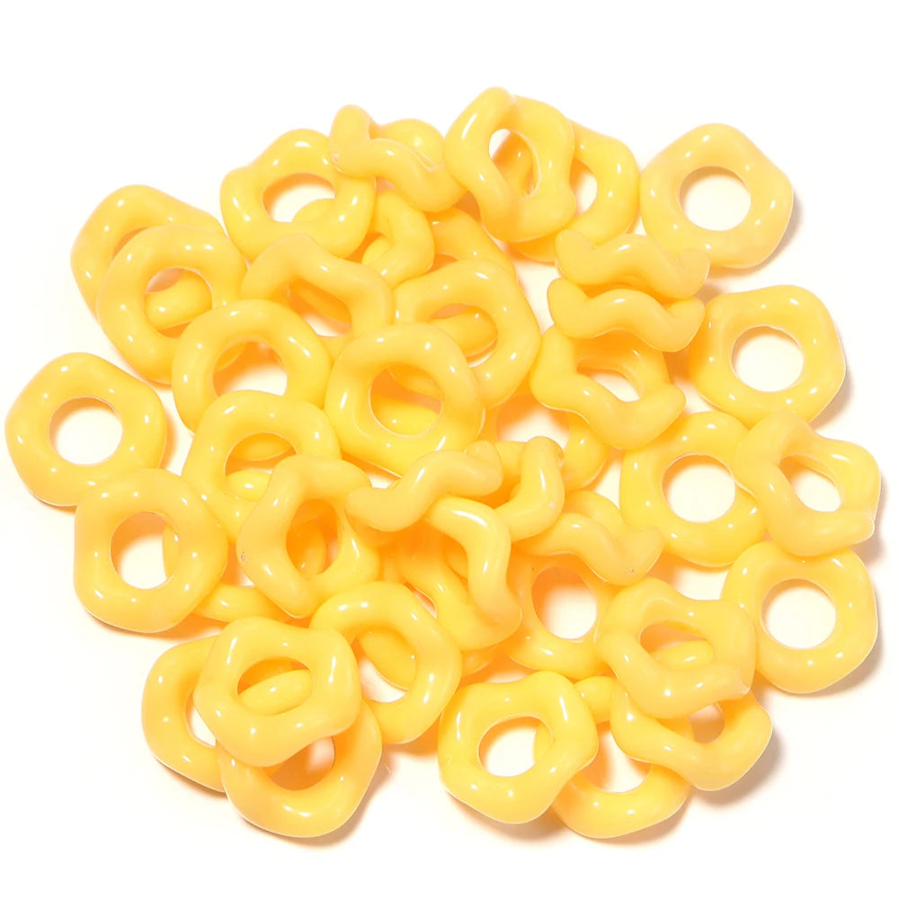 A pile of yellow, ring-shaped acrylic spacer beads for jewelry making.