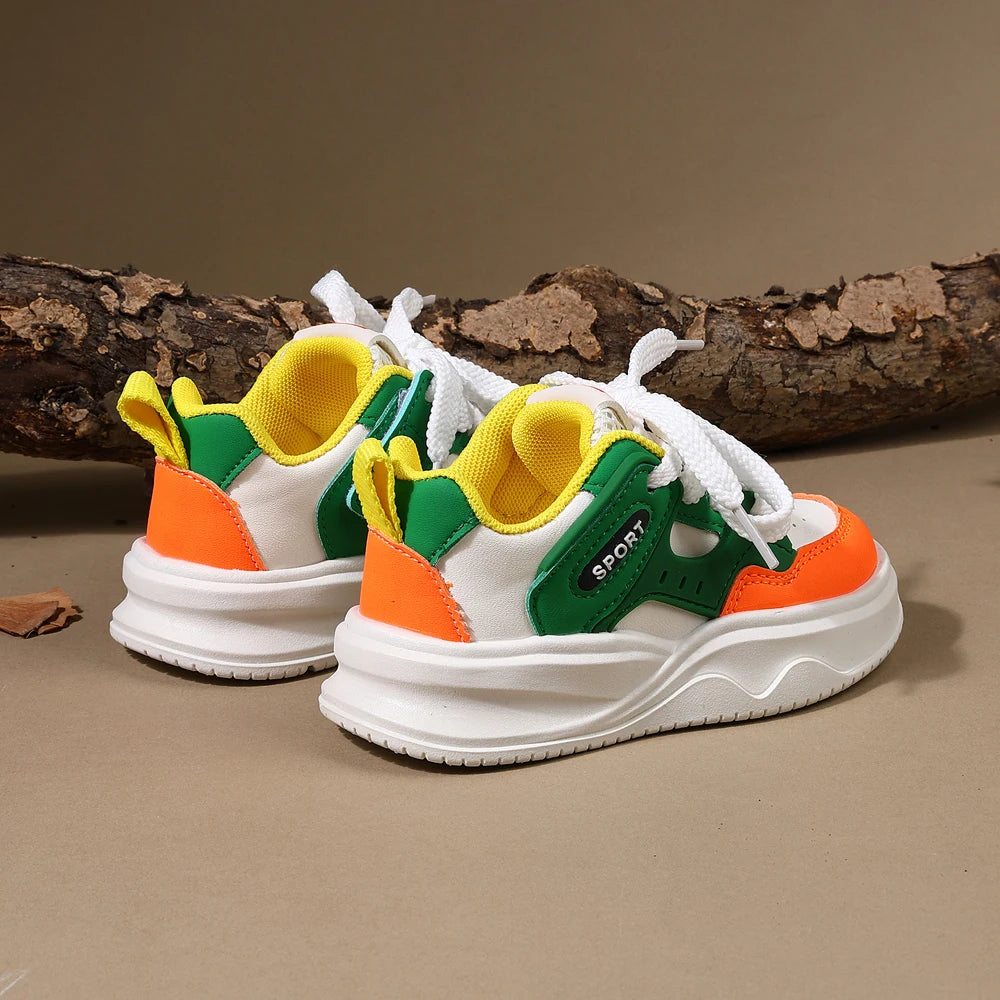 A pair of yellow, green, and orange breathable casual sneakers with white laces resting on a brown log.