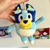A hand is holding a blue and white Bluey plush doll with large eyes and yellow nose.