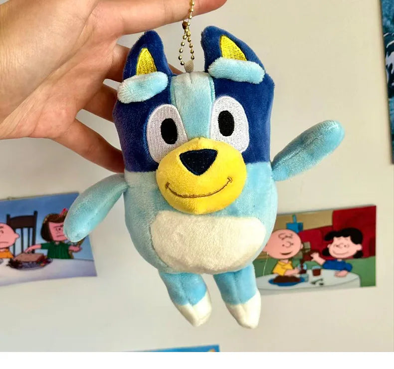 A hand is holding a blue and white Bluey plush doll with large eyes and yellow nose.