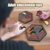 Hands are assembling a wooden hexagon tangram puzzle with various colored pieces on a wooden table.