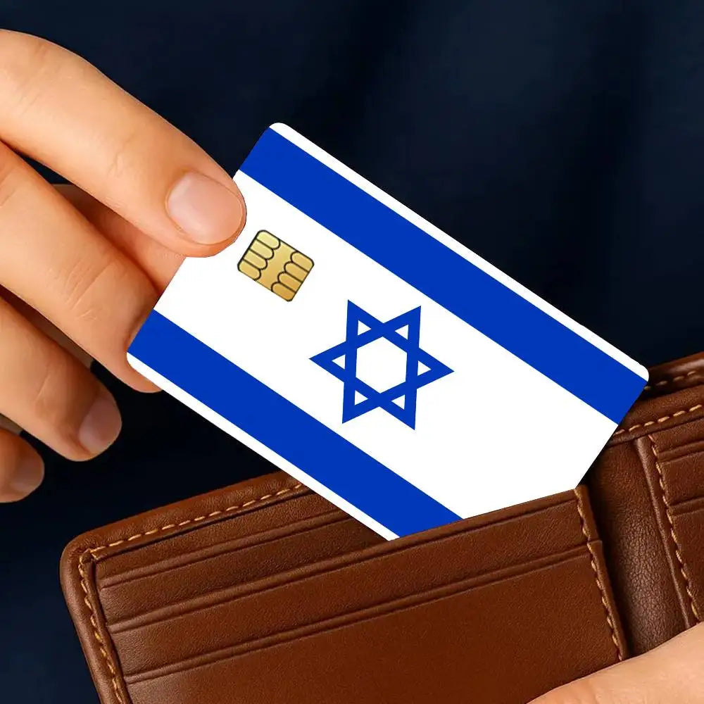 A hand holds an Israel flag credit card skin sticker set against a brown leather wallet.
