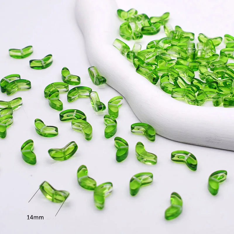 Green gradient tulip glass beads scattered on a white surface with a white mold in the background
