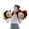 A woman holding a black and yellow bee ladybug plush toy with white wings.