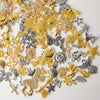 A collection of mixed metal charms including gold and silver stars, crosses, leaves, and butterflies for DIY jewelry making