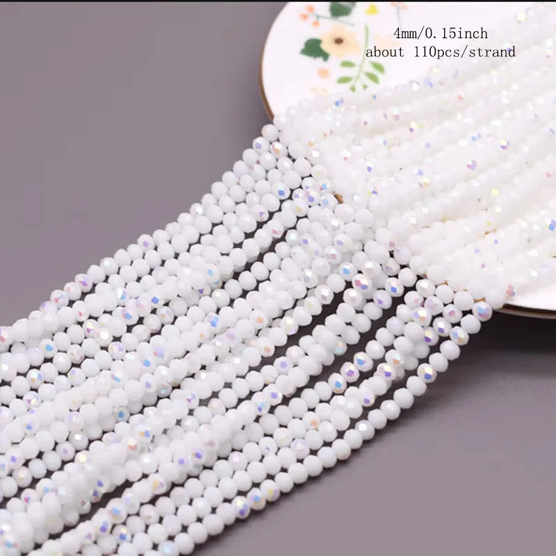 A close-up of white faceted crystal rondelle beads strung together on a white thread.
