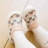A pair of beige plaid slip-on toddler shoes for first walkers with white socks