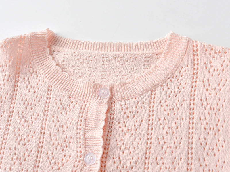 A light pink knitted cotton cardigan with a ribbed collar and button placket.