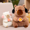 A brown capybara plush toy holding a pink lotus flower next to a white lamb plush toy.