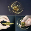 A close-up of a gold angel wings fidget spinner resting on a dark surface.