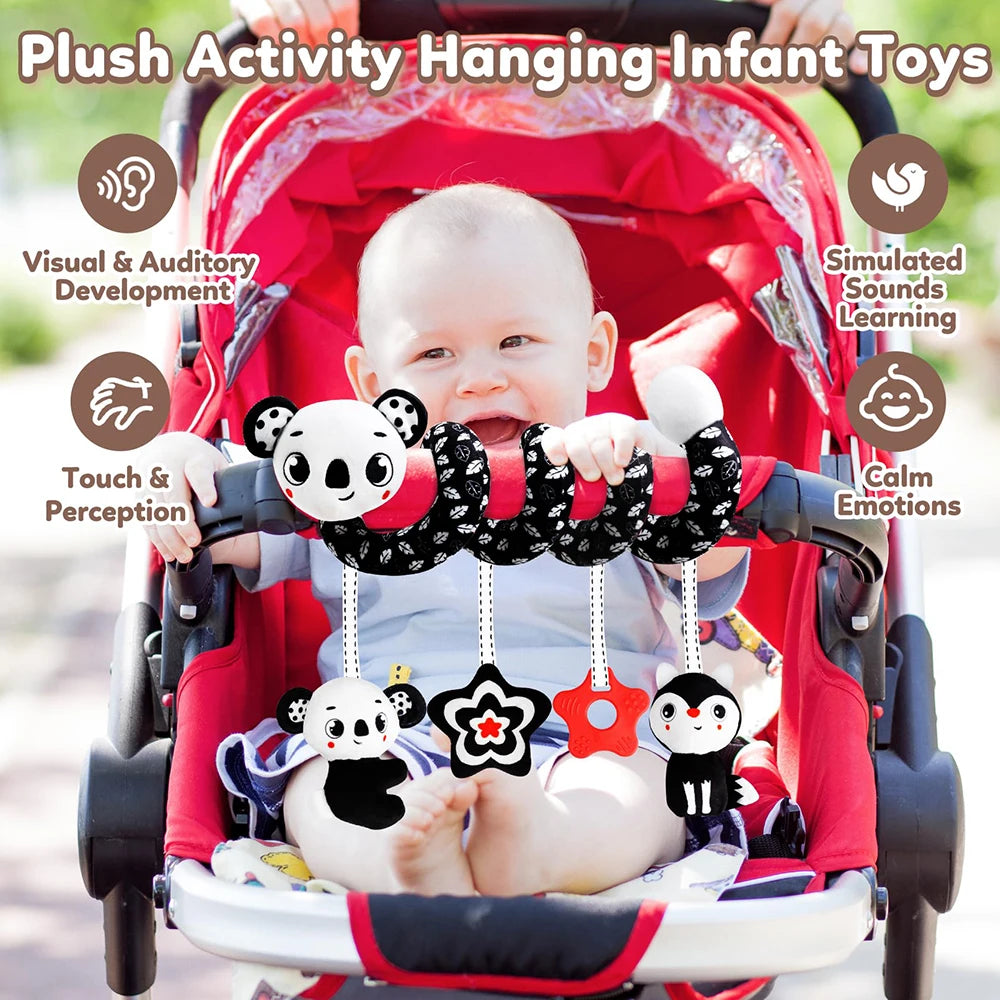 A baby is playing with plush hanging toys inside a red stroller, demonstrating visual and auditory development.