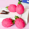 Pink dragon fruit squishy stress relief toy with green leaves on a white background.