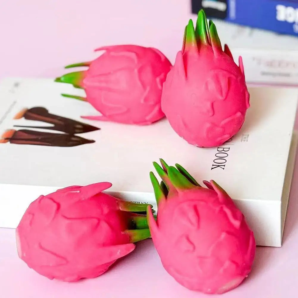 Pink dragon fruit squishy stress relief toy with green leaves on a white background.