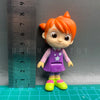 A playful cartoon PVC figurine of a child with orange hair wearing a purple outfit and green shoes, measured against a ruler.
