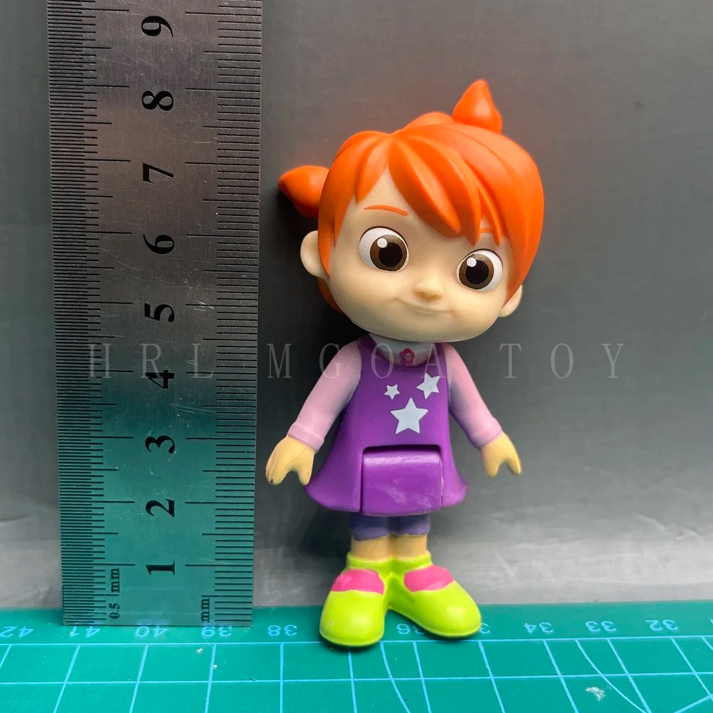 A playful cartoon PVC figurine of a child with orange hair wearing a purple outfit and green shoes, measured against a ruler.