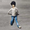 A plush doll resembling L Lawliet from Death Note, with black hair and a pale shirt, standing on a gray surface.