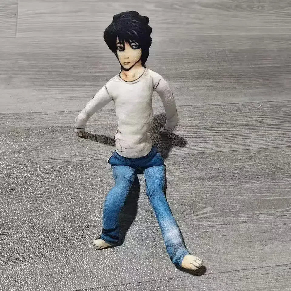 A plush doll resembling L Lawliet from Death Note, with black hair and a pale shirt, standing on a gray surface.