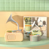 A light pink card phonograph with a white horn and a stack of colorful learning cards on a wooden surface.
