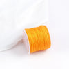 A roll of bright orange 0.8mm cotton nylon macrame cord for jewelry making and crafts.