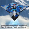 A blue and gray stunt glider with LED lights is shown in flight against a snowy background.