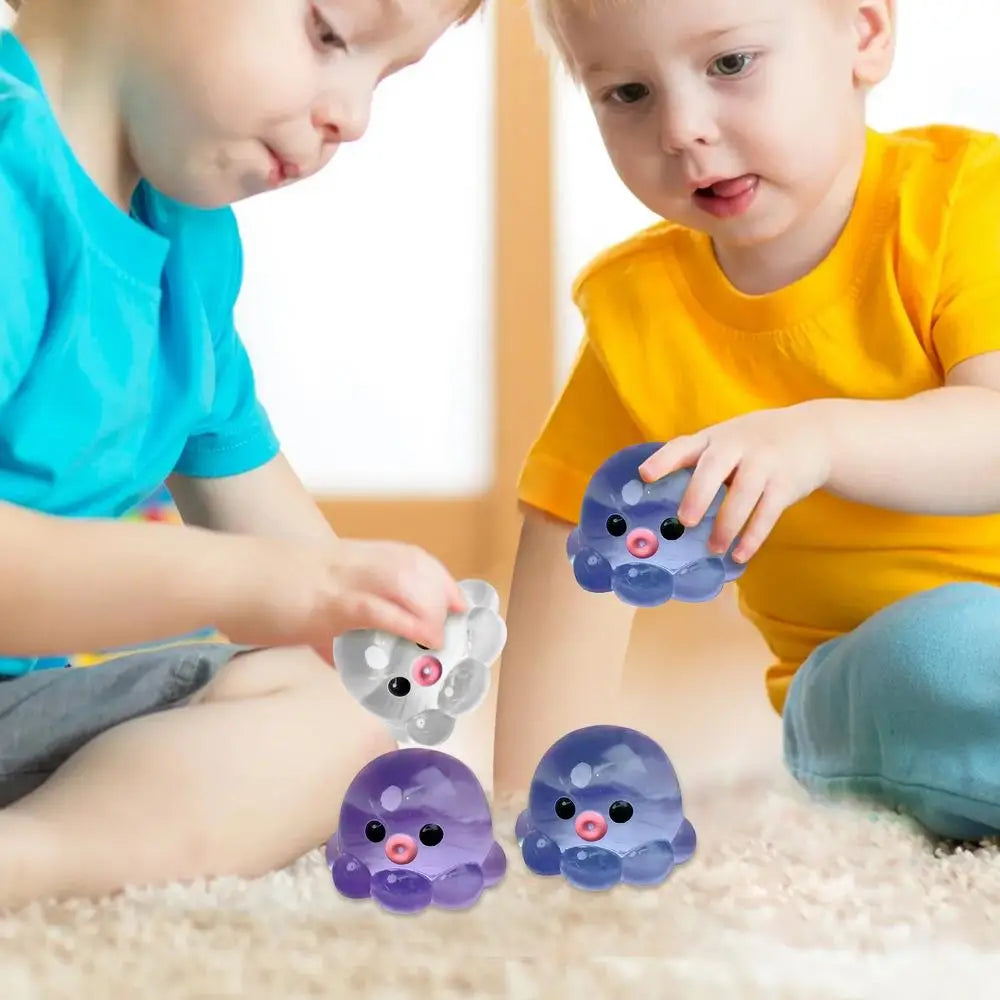 Two toddlers interact with purple and blue octopus squishy stress balls on a light-colored rug.